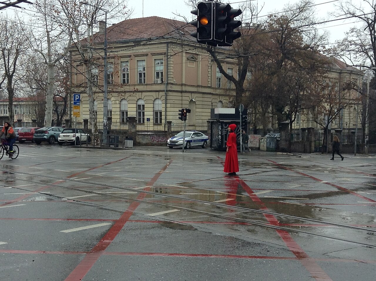 Una ragazza vestita di rosso ferma in mezzo a un incrocio di Belgrado